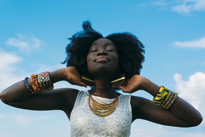 profile photo of a woman against a blue sky with gold earrings 